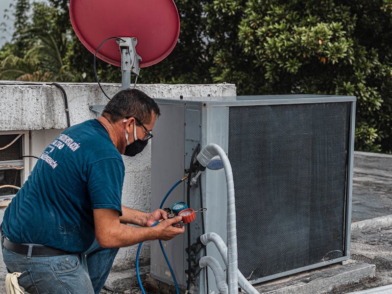 HVAC technician servicing an outdoor air conditioning unit
