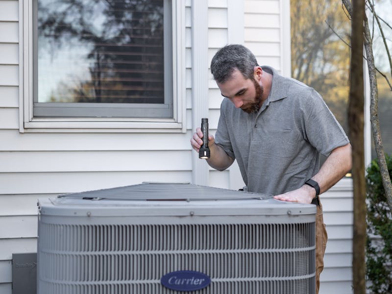 Technician inspecting outdoor residential air conditioning unit